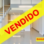 Sala diáfana con escaleras y cocina americana al fondo. En primer plano figura la etiqueta de VENDIDO