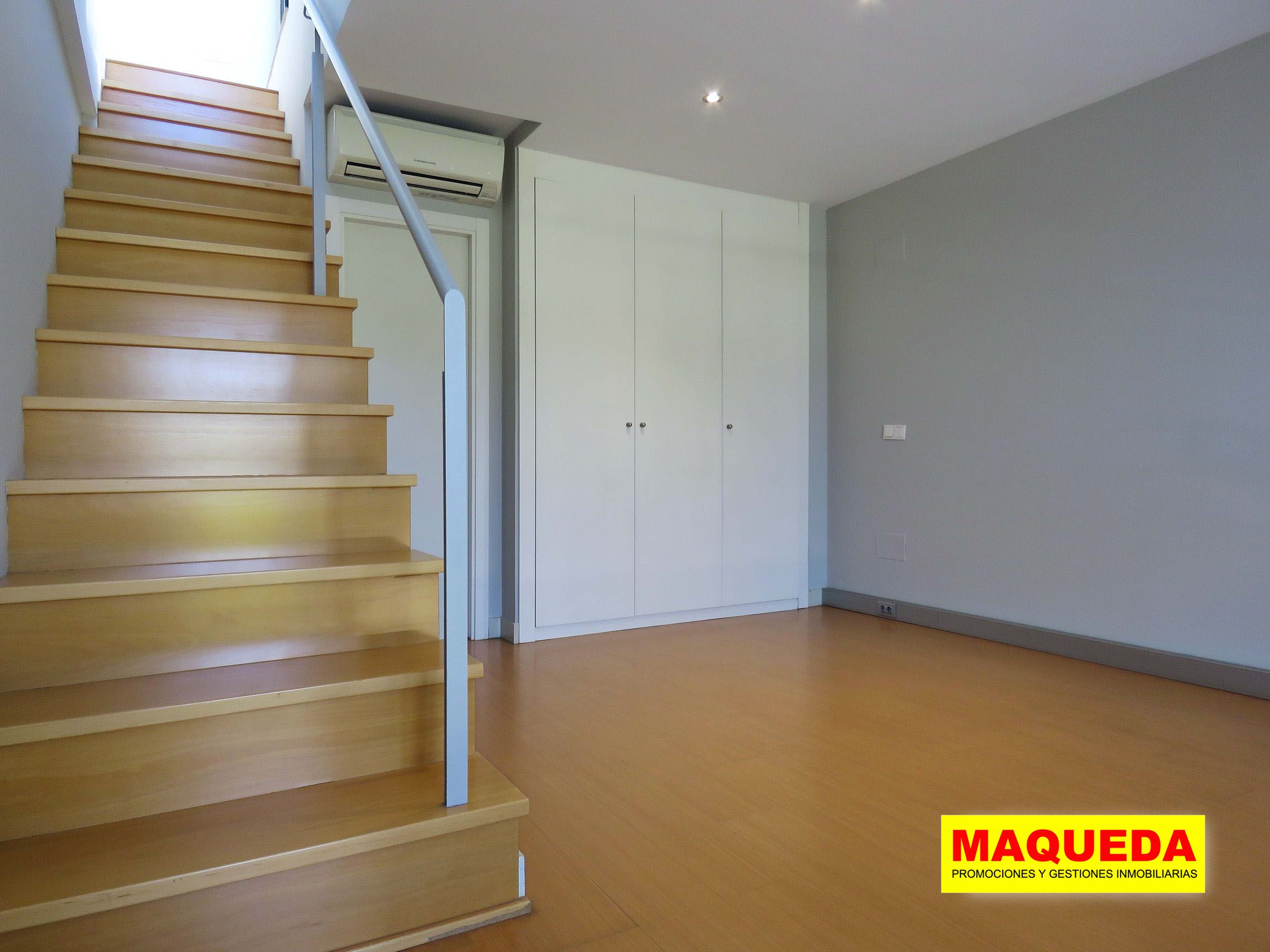 Habitación en planta alta con suelo de tarima, armario empotrado y aire acondicionado. A la izquierda, tramo de escalera a la azotea
