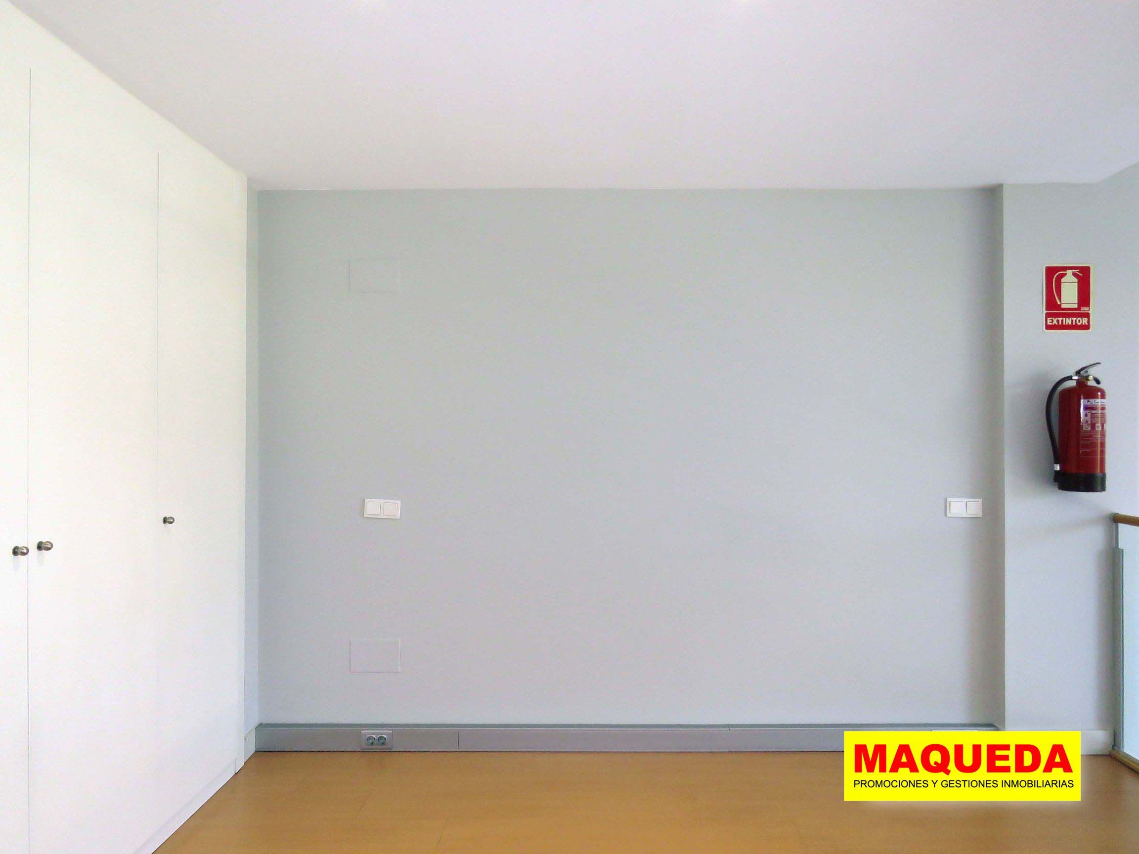 Habitación en planta alta con suelo de tarima, armario empotrado a la izquierda y extintor a la derecha