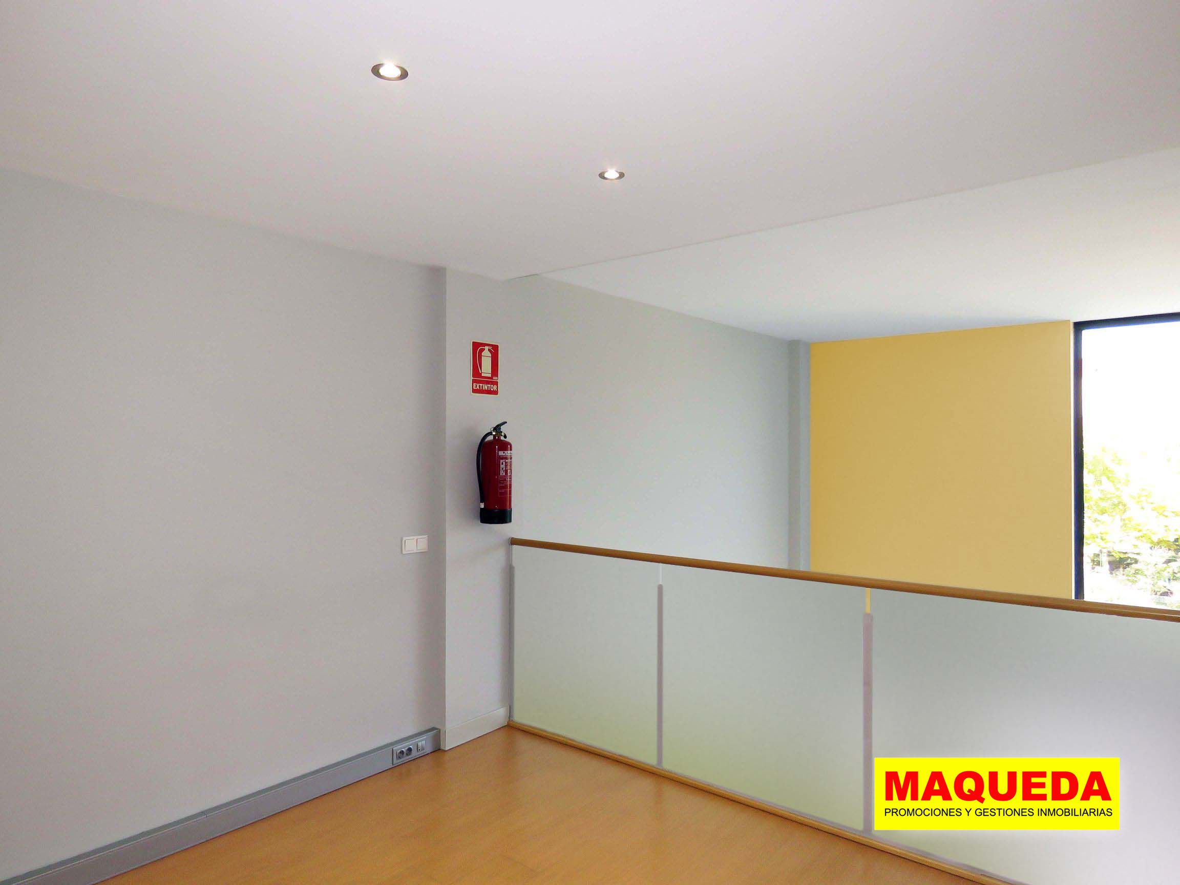 Habitación en planta alta con suelo de tarima, barandilla y extintor de incendios