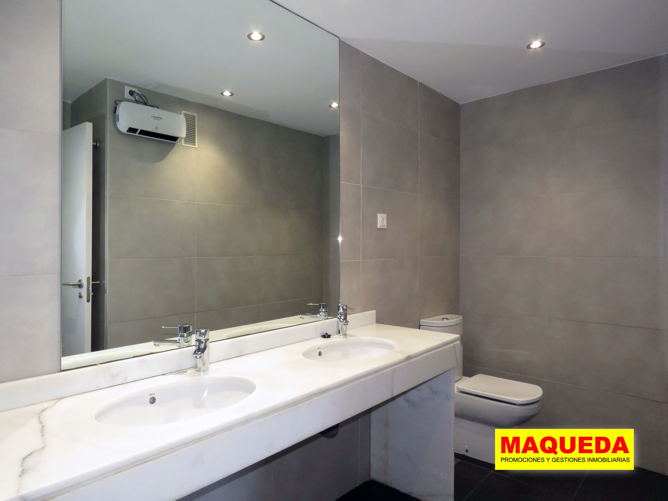 Baño en planta alta con encimera de mármol, doble lavabo y amplio espejo