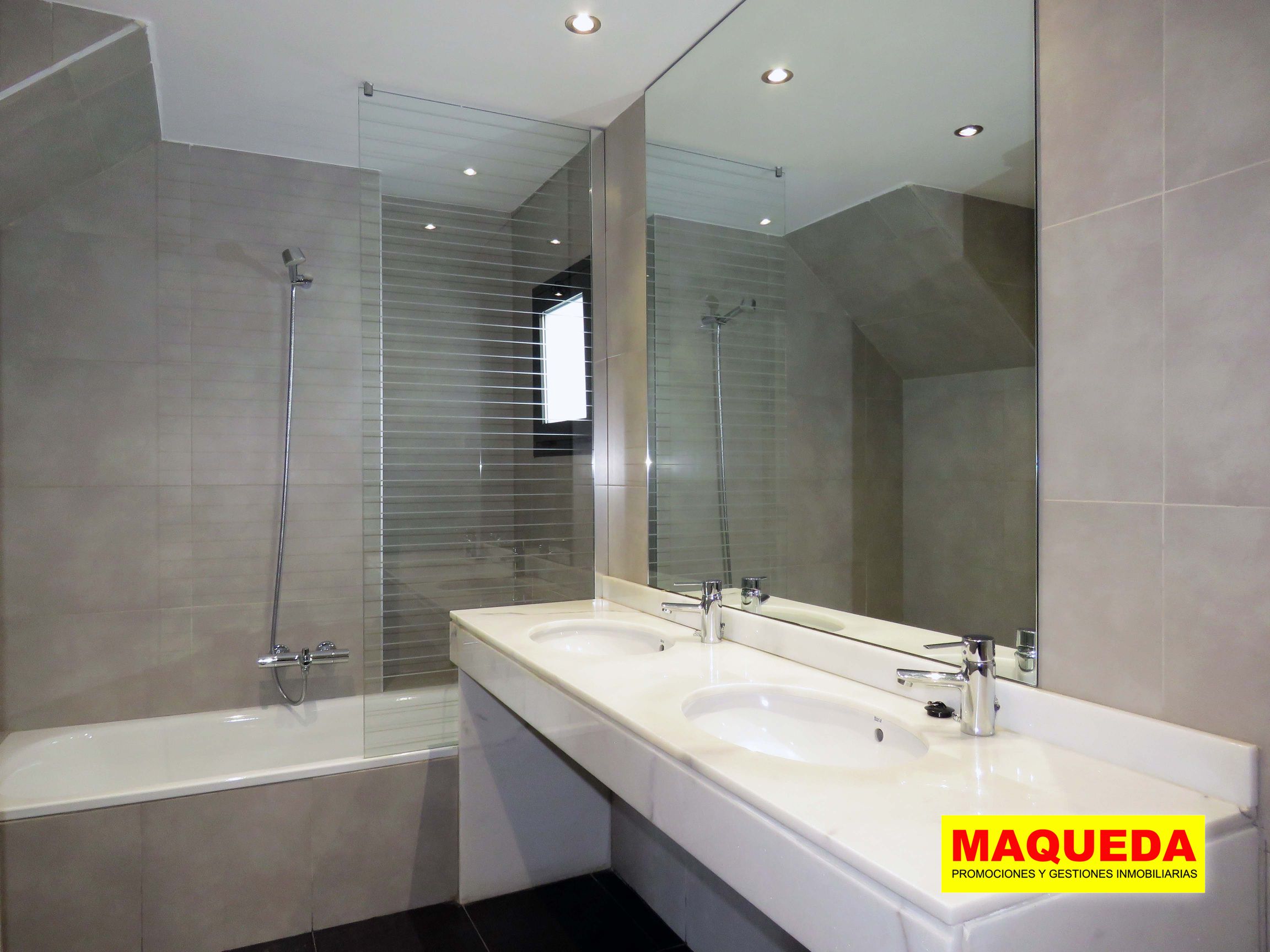 Baño en planta alta con encimera de mármol, doble lavabo, amplio espejo, bañera con mampara de cristal y ventana