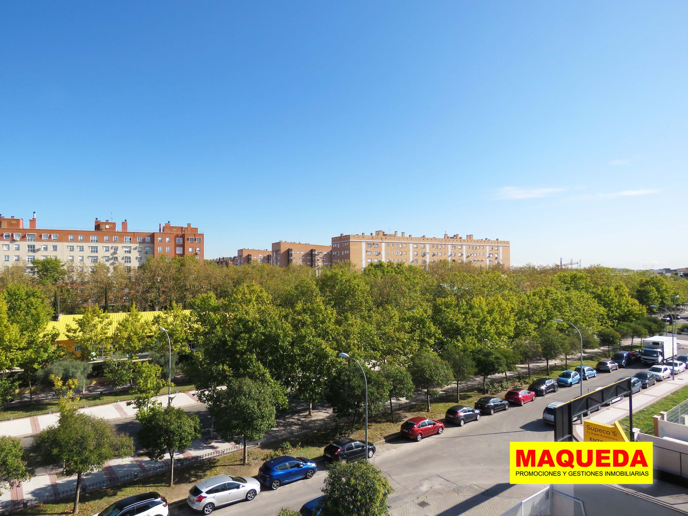 Vistas a la avenida de Leganés con zona arbolada y edificio de viviendas al fondo