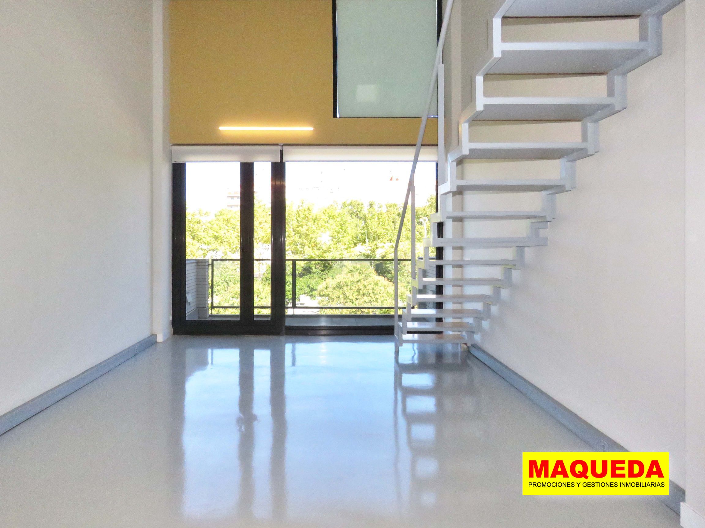 Sala diáfana con escaleras y enorme ventanal con acceso a terraza