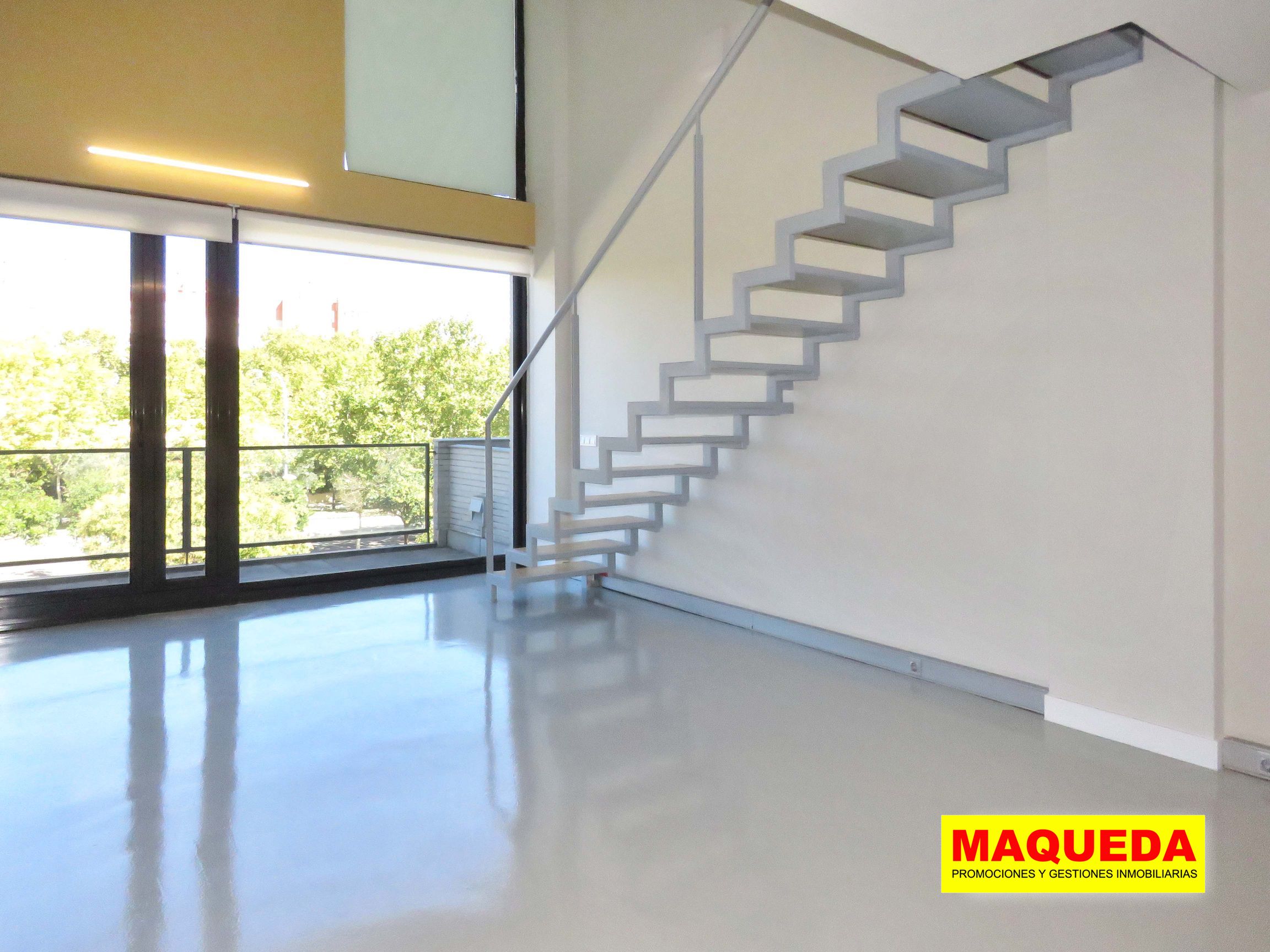 Sala diáfana con escaleras y enorme ventanal con acceso a terraza