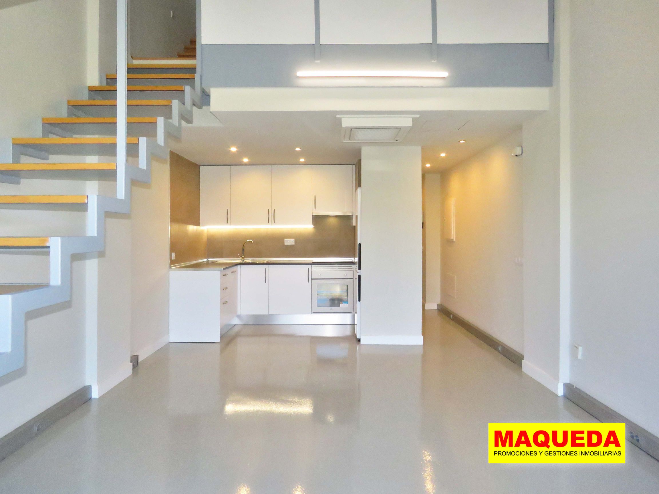 Sala diáfana con escaleras y cocina americana al fondo