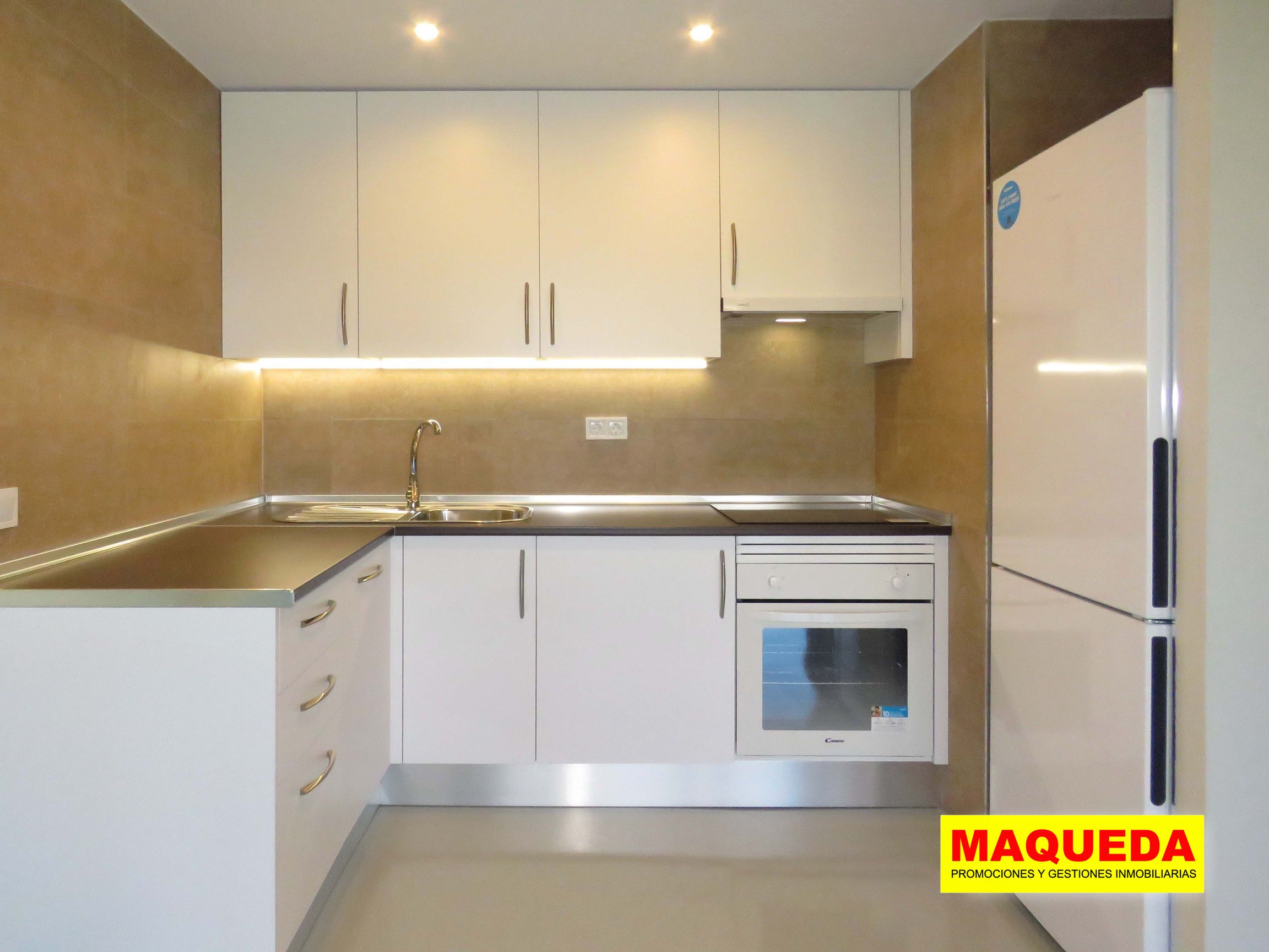 Primer plano de la cocina amueblada con iluminación bajo encimera, horno y frigorífico
