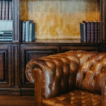 Sillón de cuero marrón y estantería de madera con libros