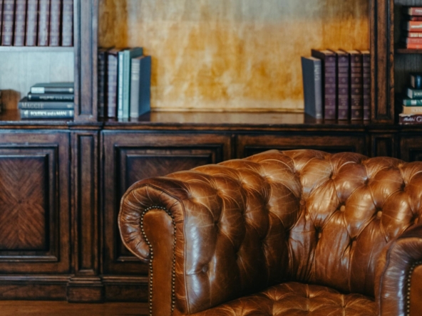 Sillón de cuero marrón y estantería de madera con libros