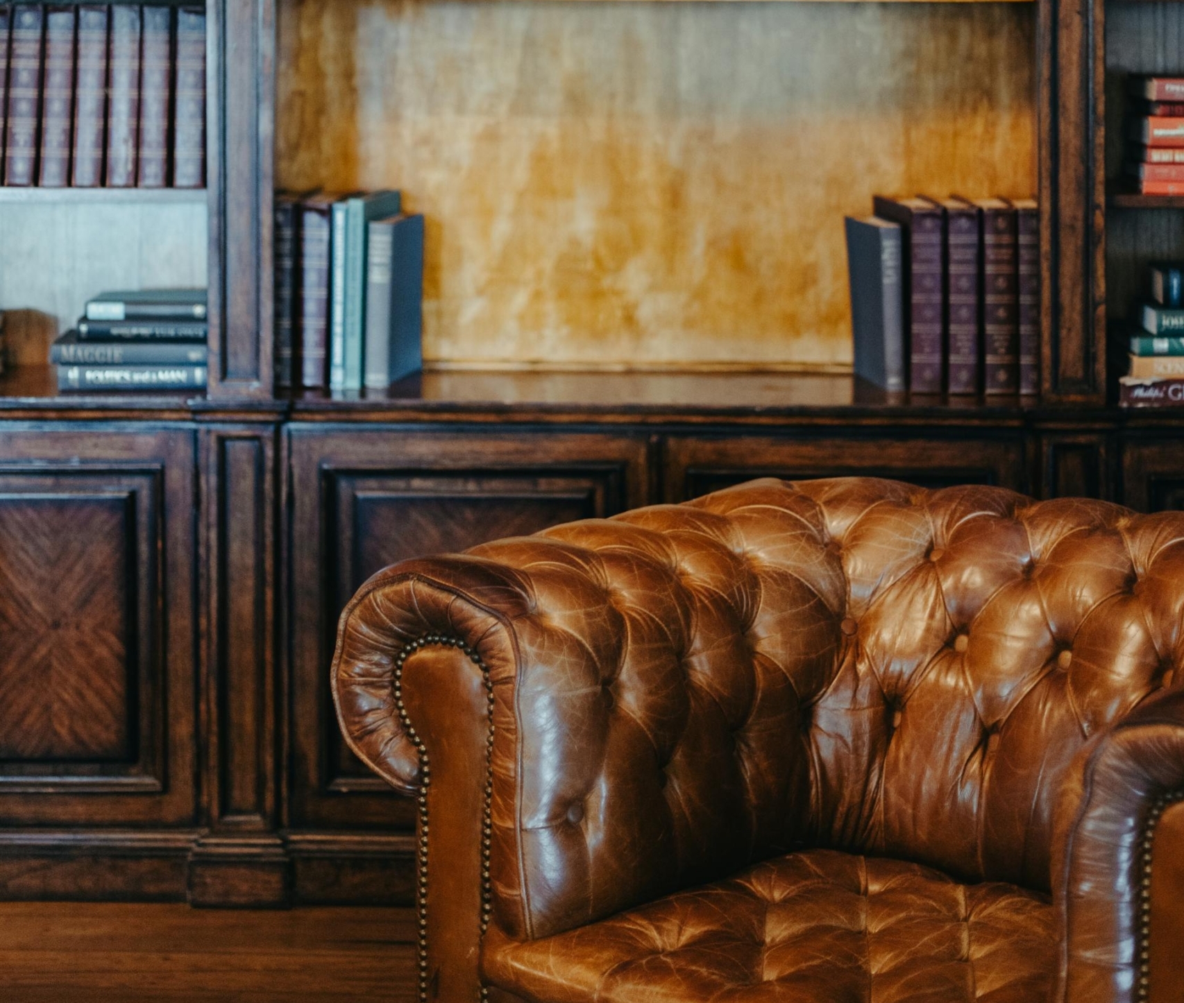 Sillón de cuero marrón y estantería de madera con libros
