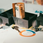 Sobre un documento de inversión, maqueta de una casa con billetes en el interior