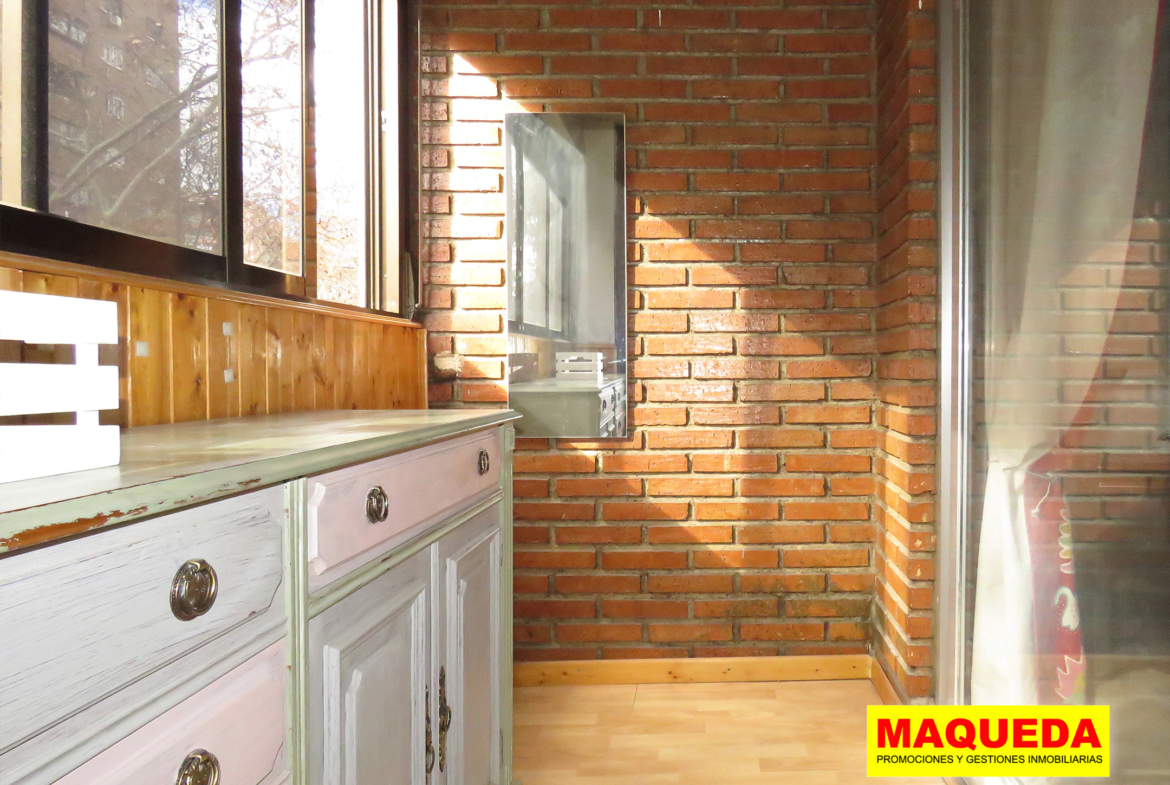Terraza acristalada con pared de ladrillo visto