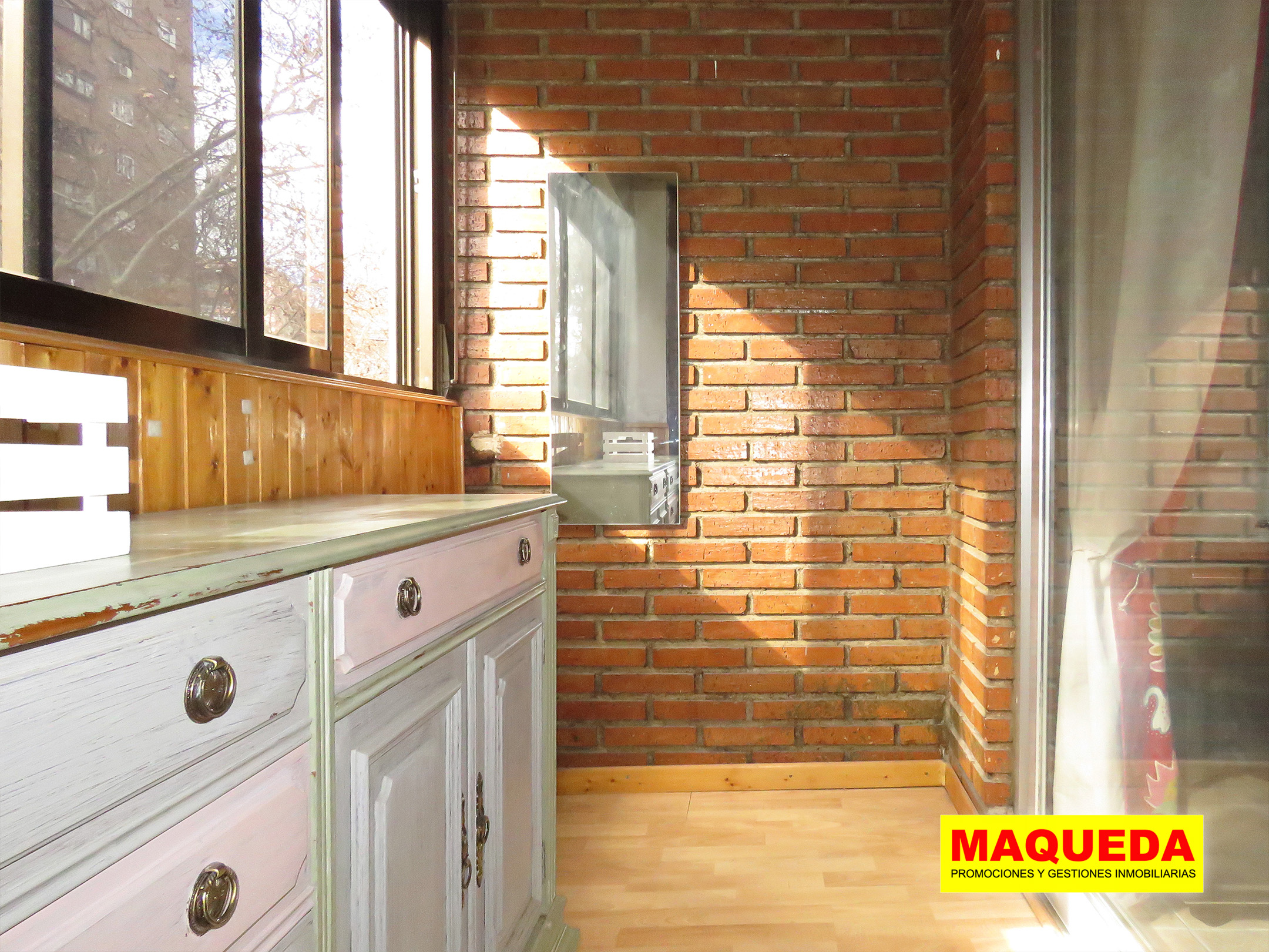 Terraza acristalada con pared de ladrillo visto