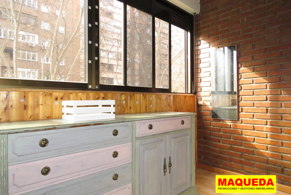 Terraza acristalada con pared de ladrillo visto y amplia cristalera