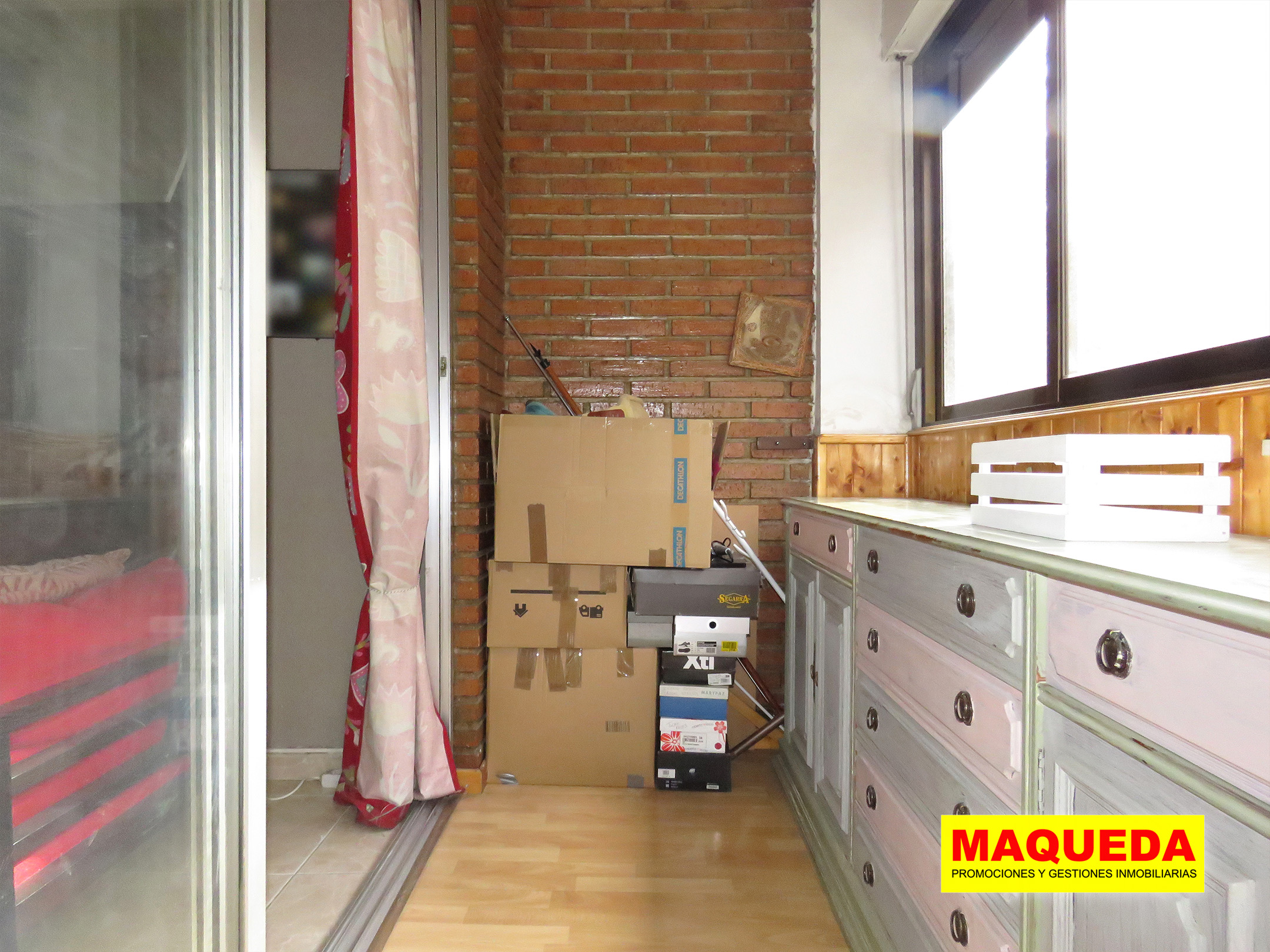 Terraza acristalada con pared de ladrillo visto y puerta corredera del salón