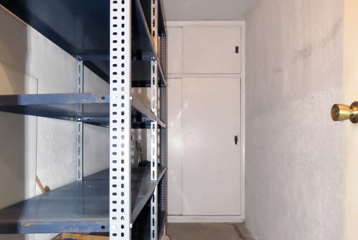 Trastero de la vivienda con estanterías metálicas y armario al fondo