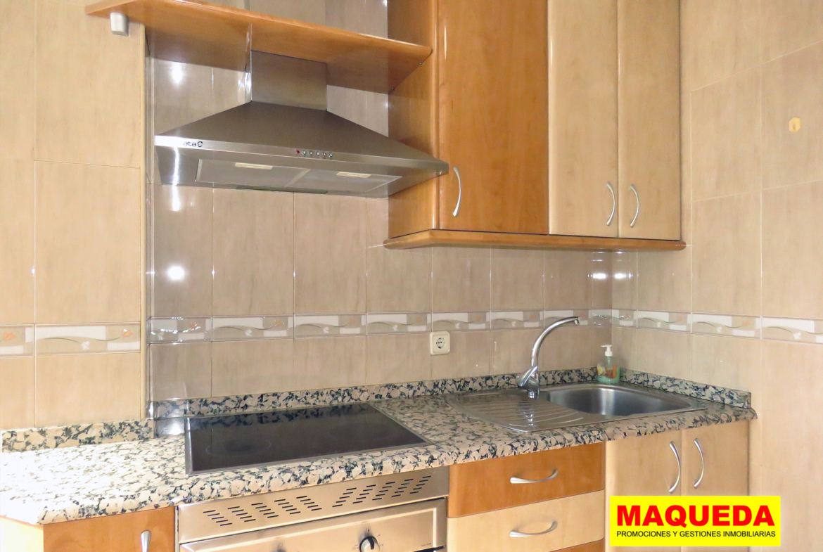 Cocina amueblada con encimera de piedra y vitroceramica