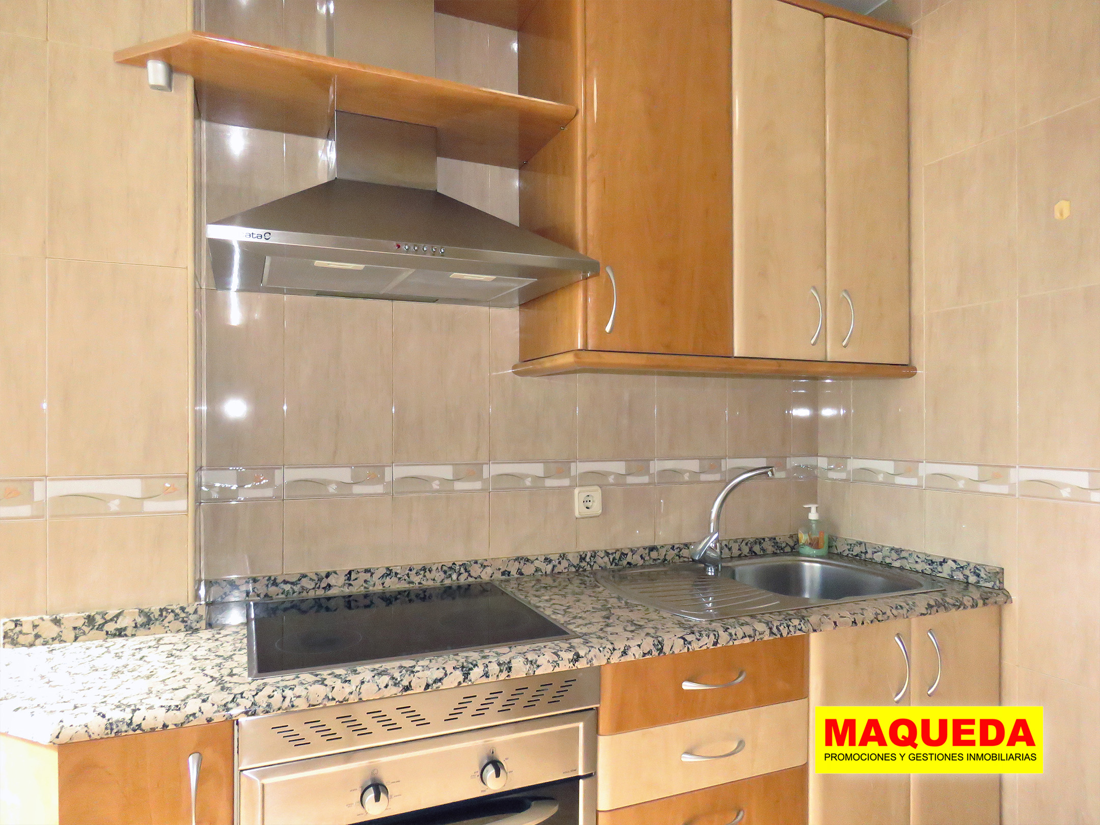 Cocina amueblada con encimera de piedra y vitroceramica