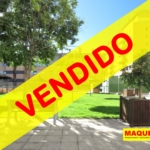 Interior de la urbanización con zonas verdes, banco, césped y árboles con etiqueta de VENDIDO