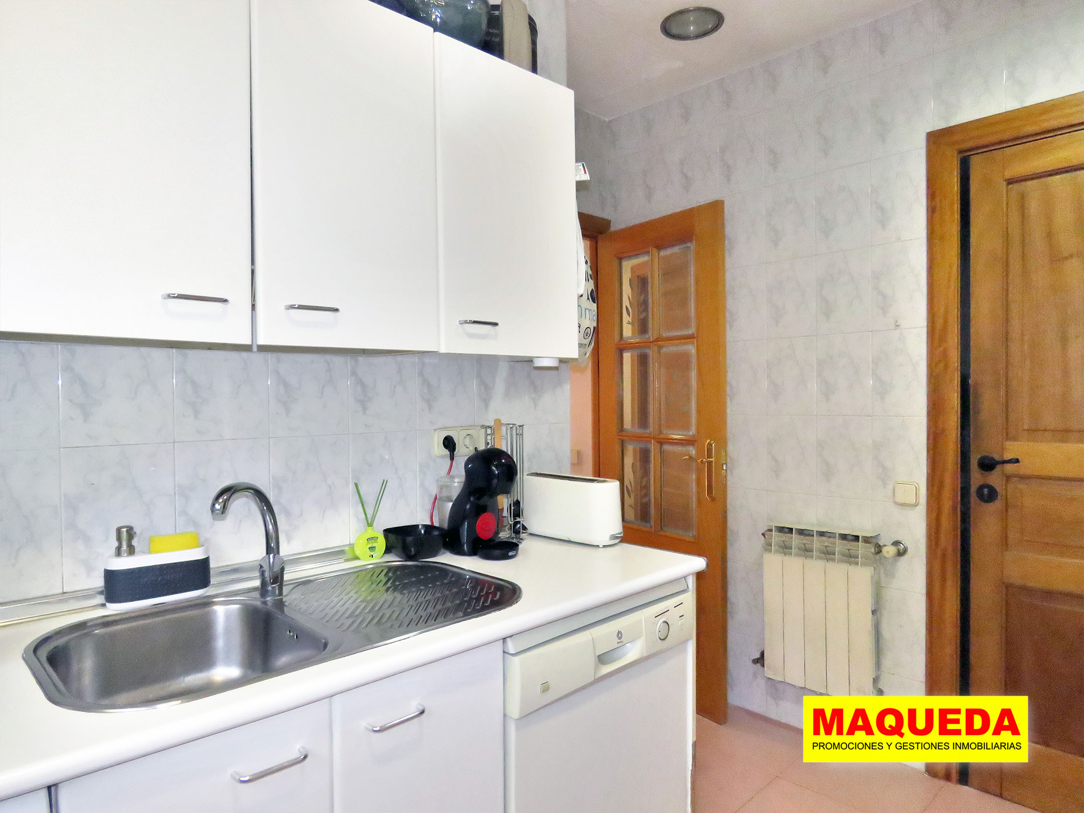 Lateral de la cocina con muebles blancos