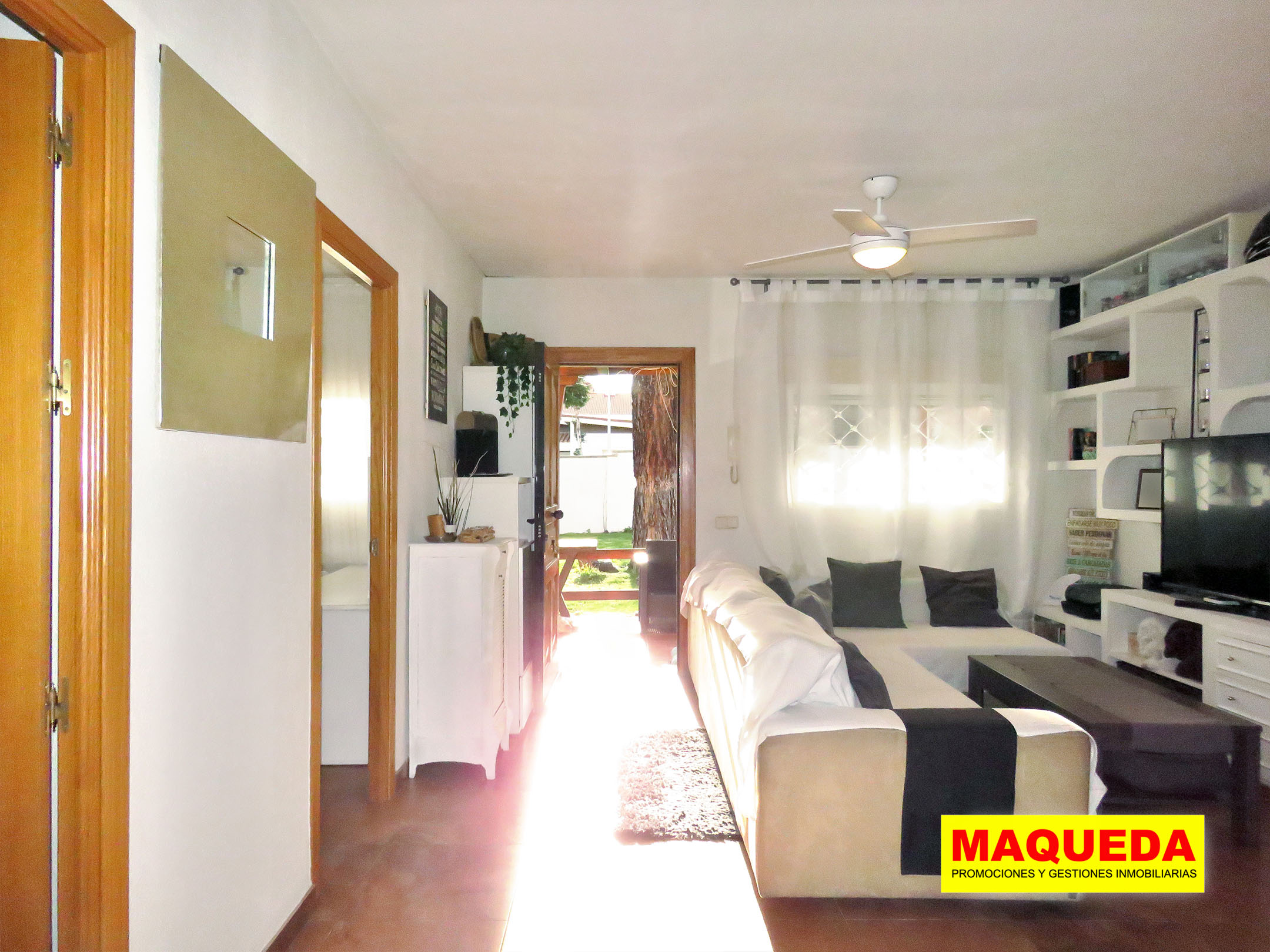 Puerta abierta de acceso a la casa con jardín al fondo