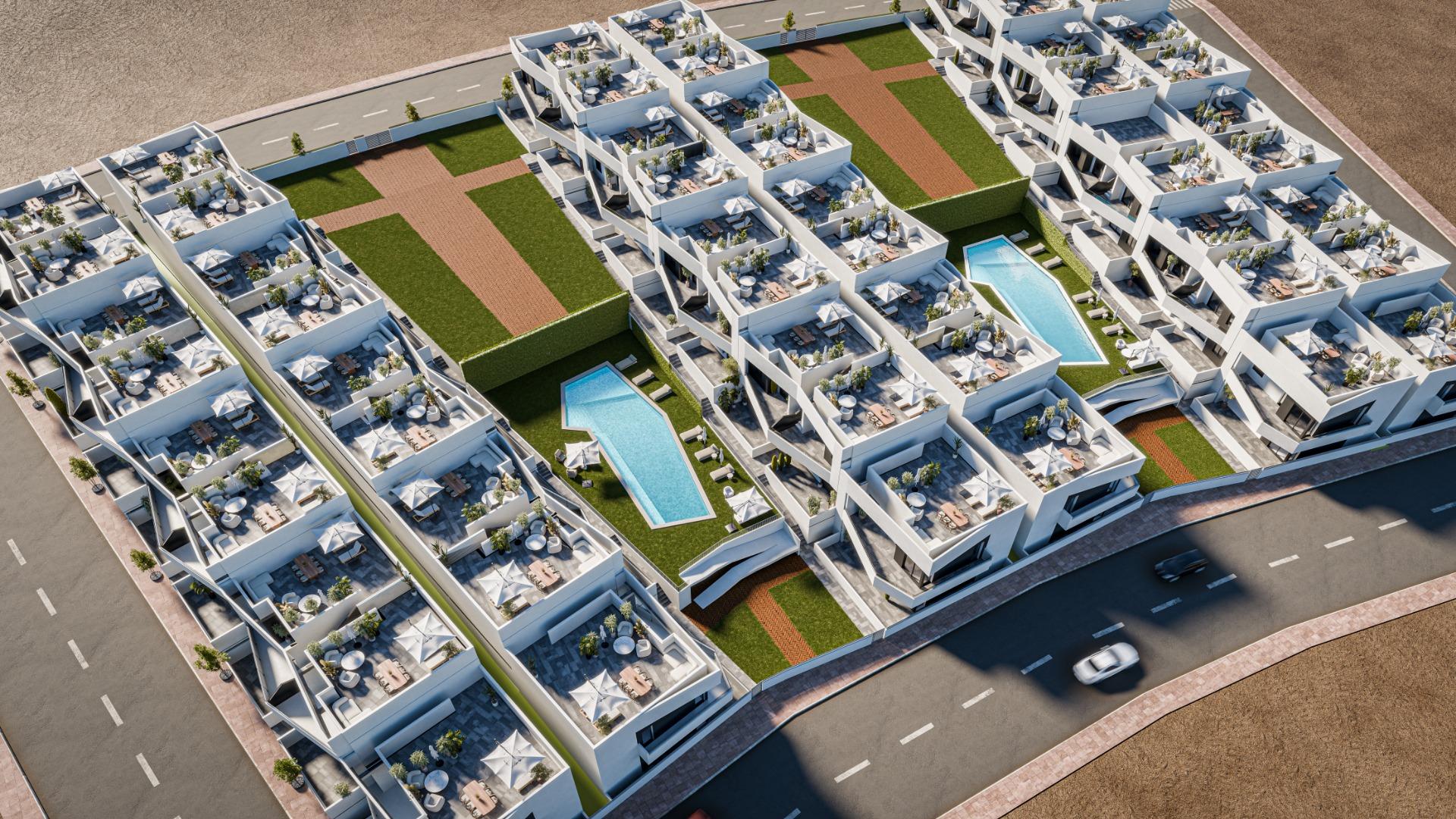 Aerial view of a modern residential complex with white multi-storey buildings, private terraces, green courtyards, and two triangular swimming pools amid landscaped spaces.