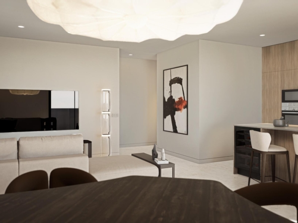 Open-plan living area with a beige sectional sofa, wall-mounted TV, and an abstract framed artwork near a modern kitchen island.