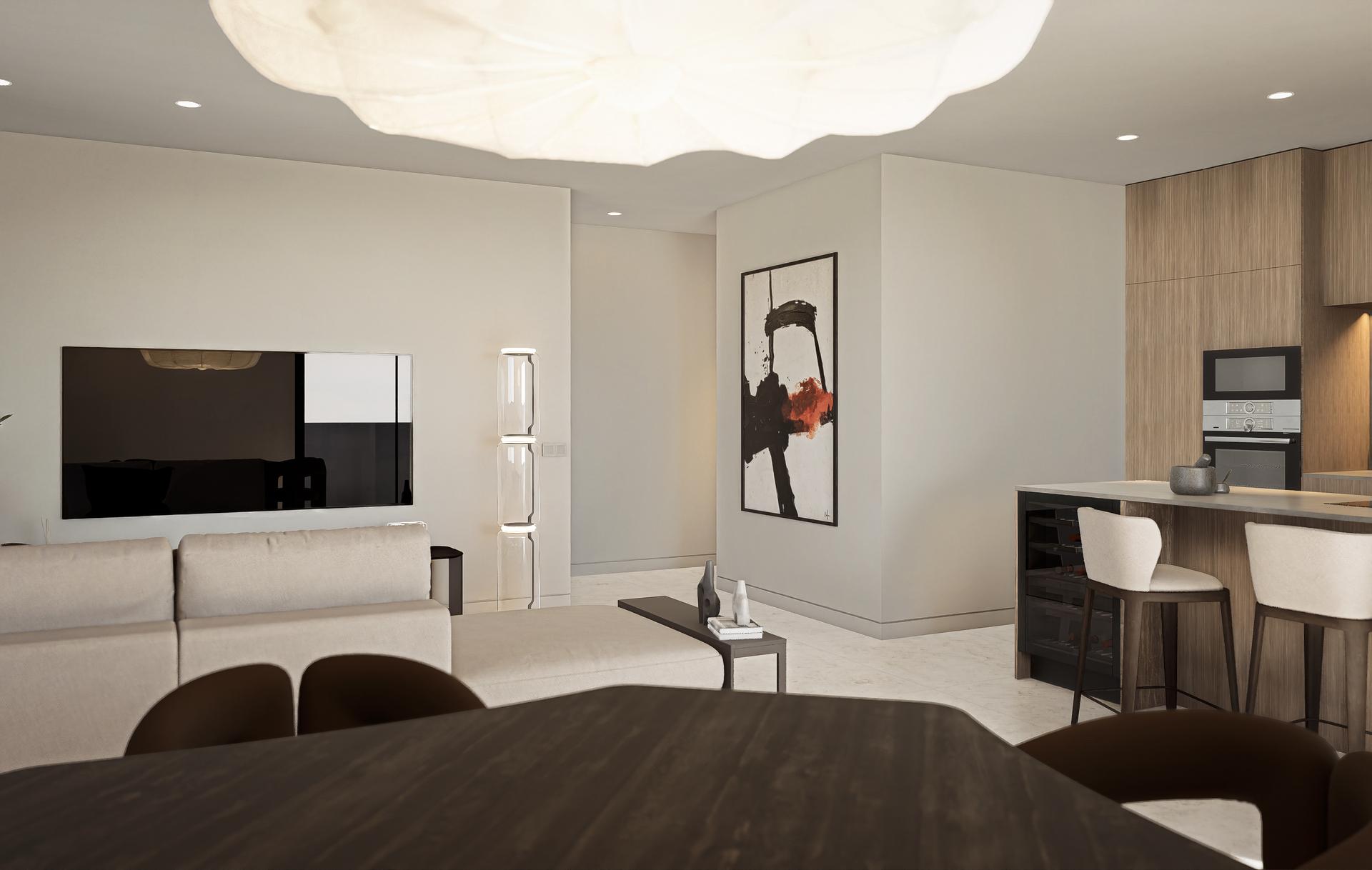 Open-plan living area with a beige sectional sofa, wall-mounted TV, and an abstract framed artwork near a modern kitchen island.