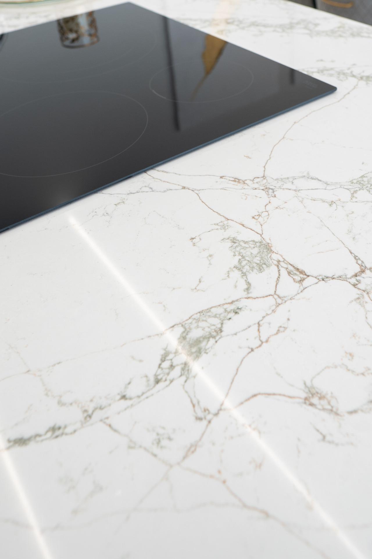 Induction cooktop with circular heating zones on a white marble countertop.