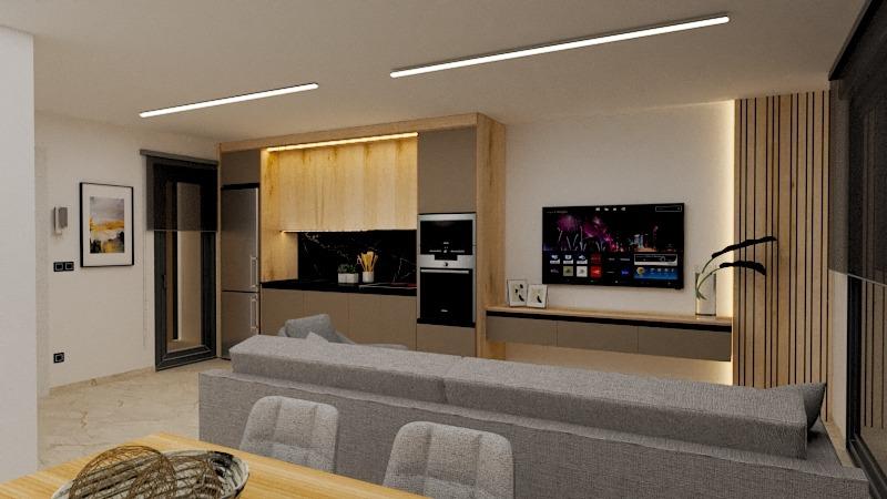 Open-concept living space with a gray sectional facing a wall-mounted TV, a wooden kitchen, and a dining table in the foreground.