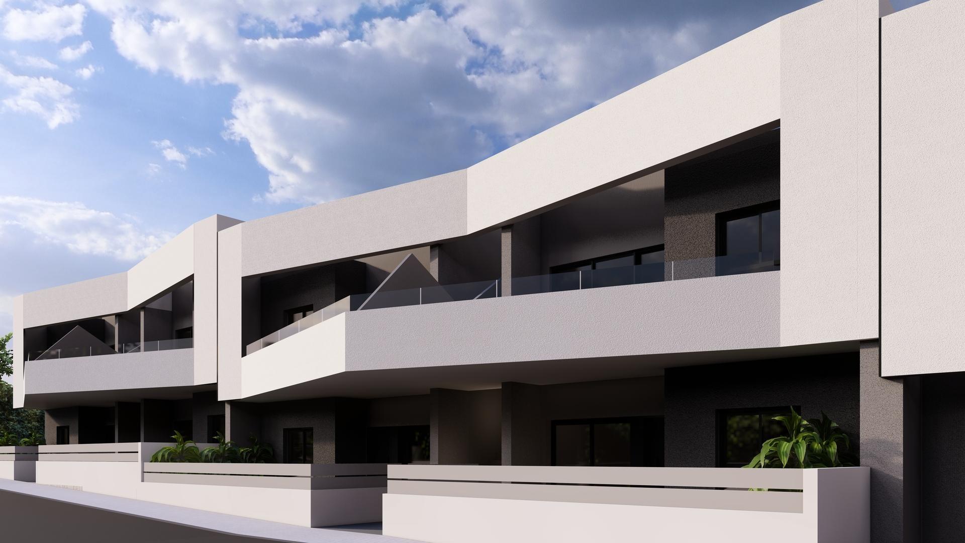 Modern white apartment building with multiple balconies and glass railings under a blue sky.