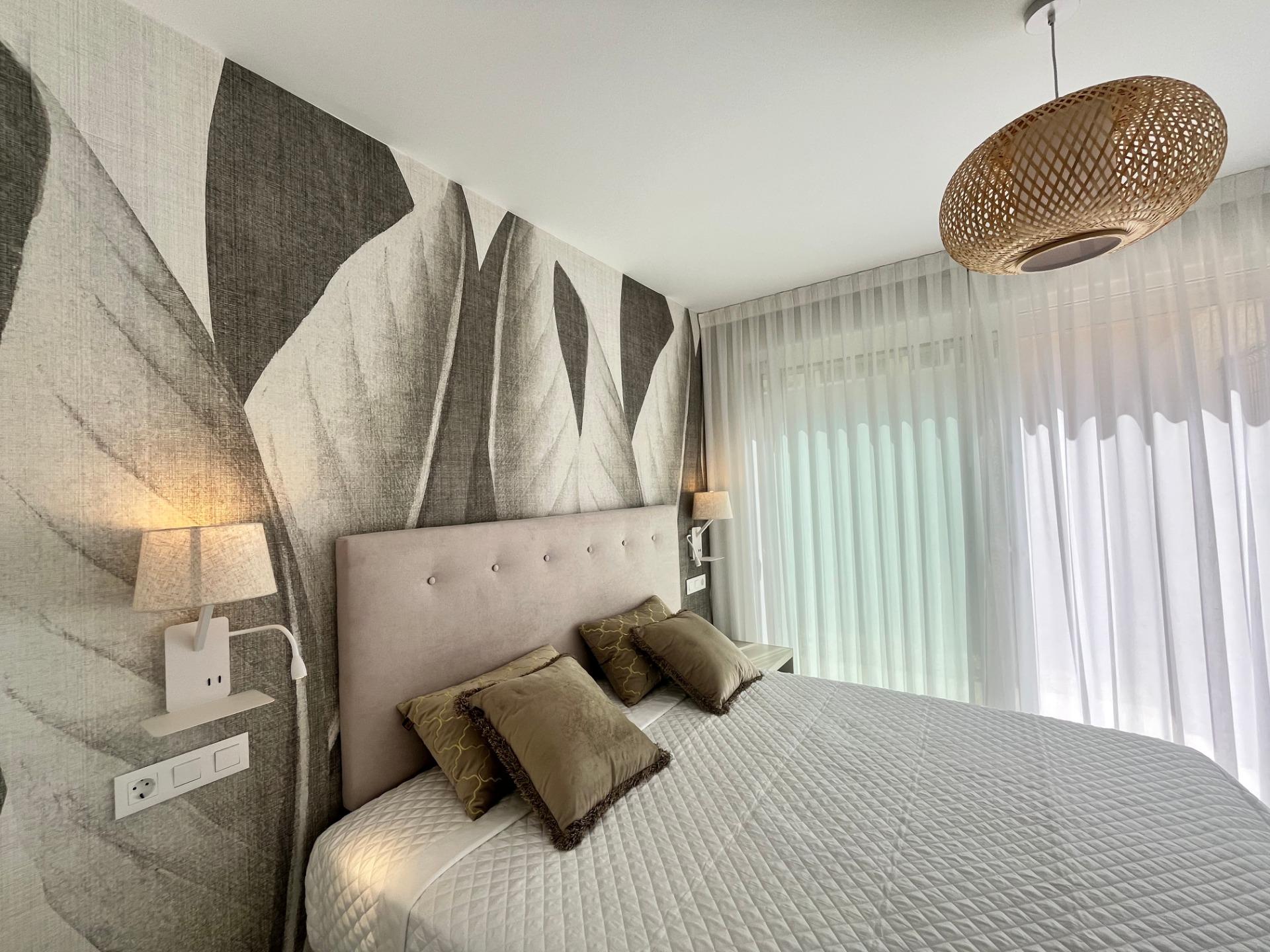 Hotel room with two twin beds, beige headboard, and geometric wallpaper under warm bedside lighting.