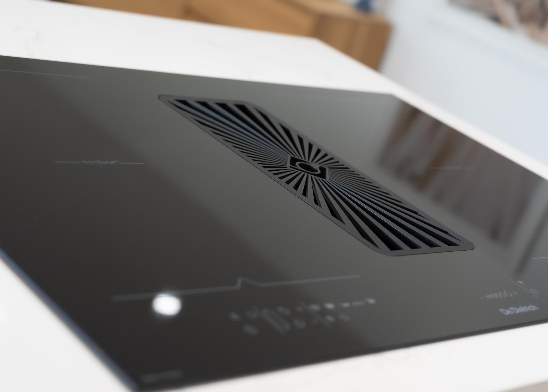 Close-up of a black electronic panel featuring a rectangular, radiating vent grille at the center.
