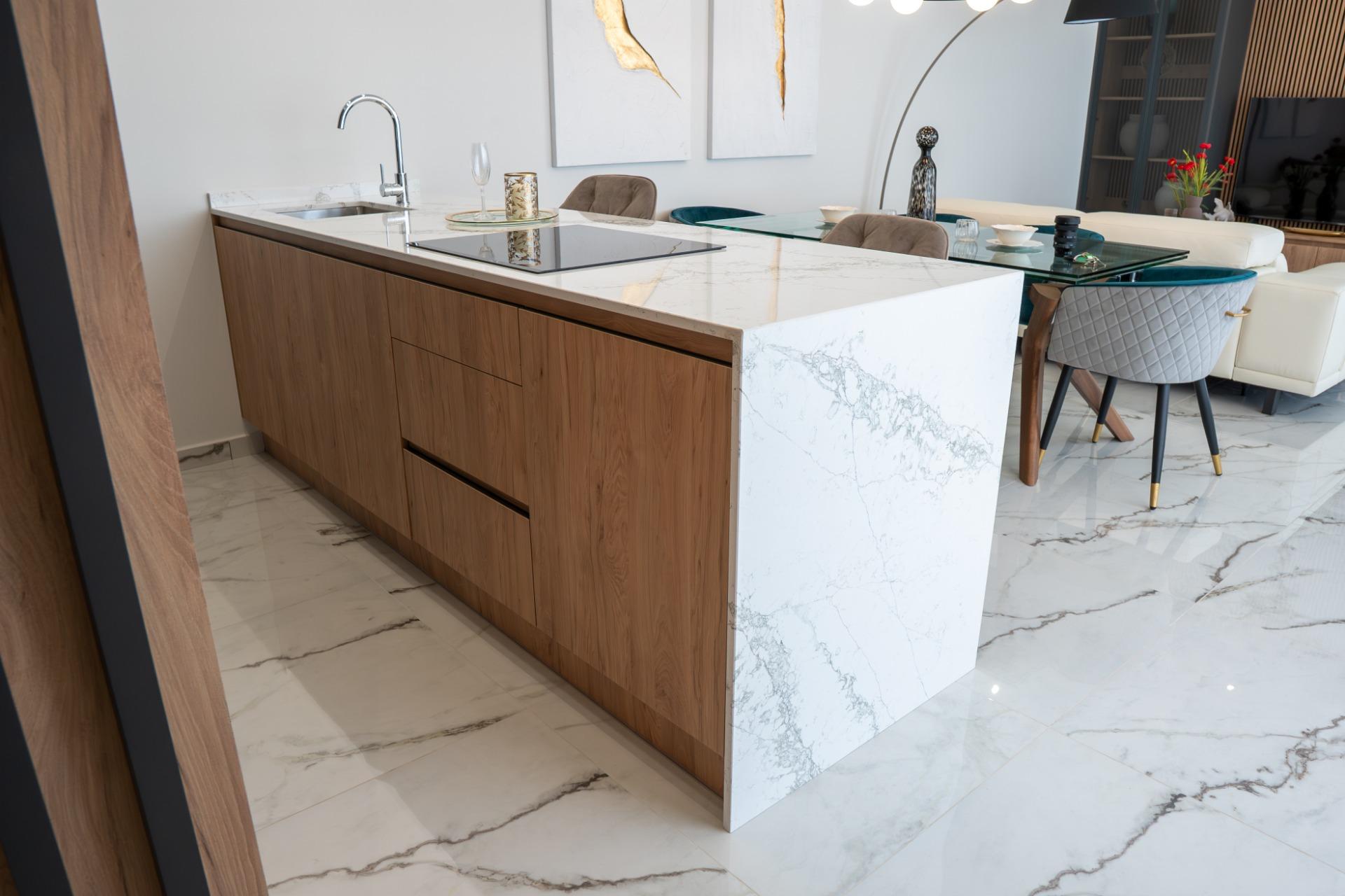 Open-concept kitchen with a marble island, wood base cabinets, and a marble-topped peninsula.