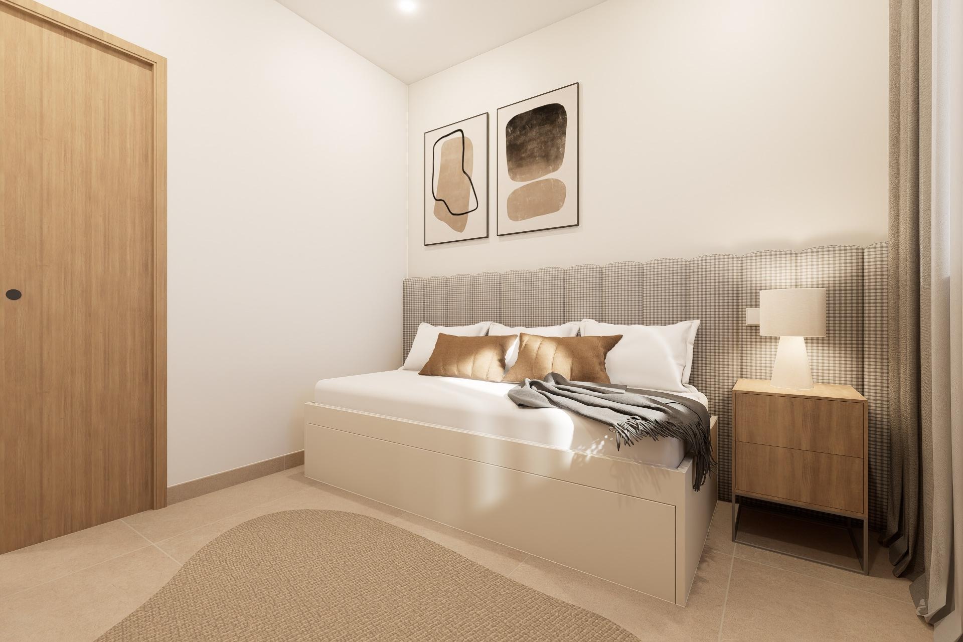 Minimal bedroom with a white platform bed, checkered padded headboard, two abstract art prints, beige pillows, and a wooden nightstand with a lamp.