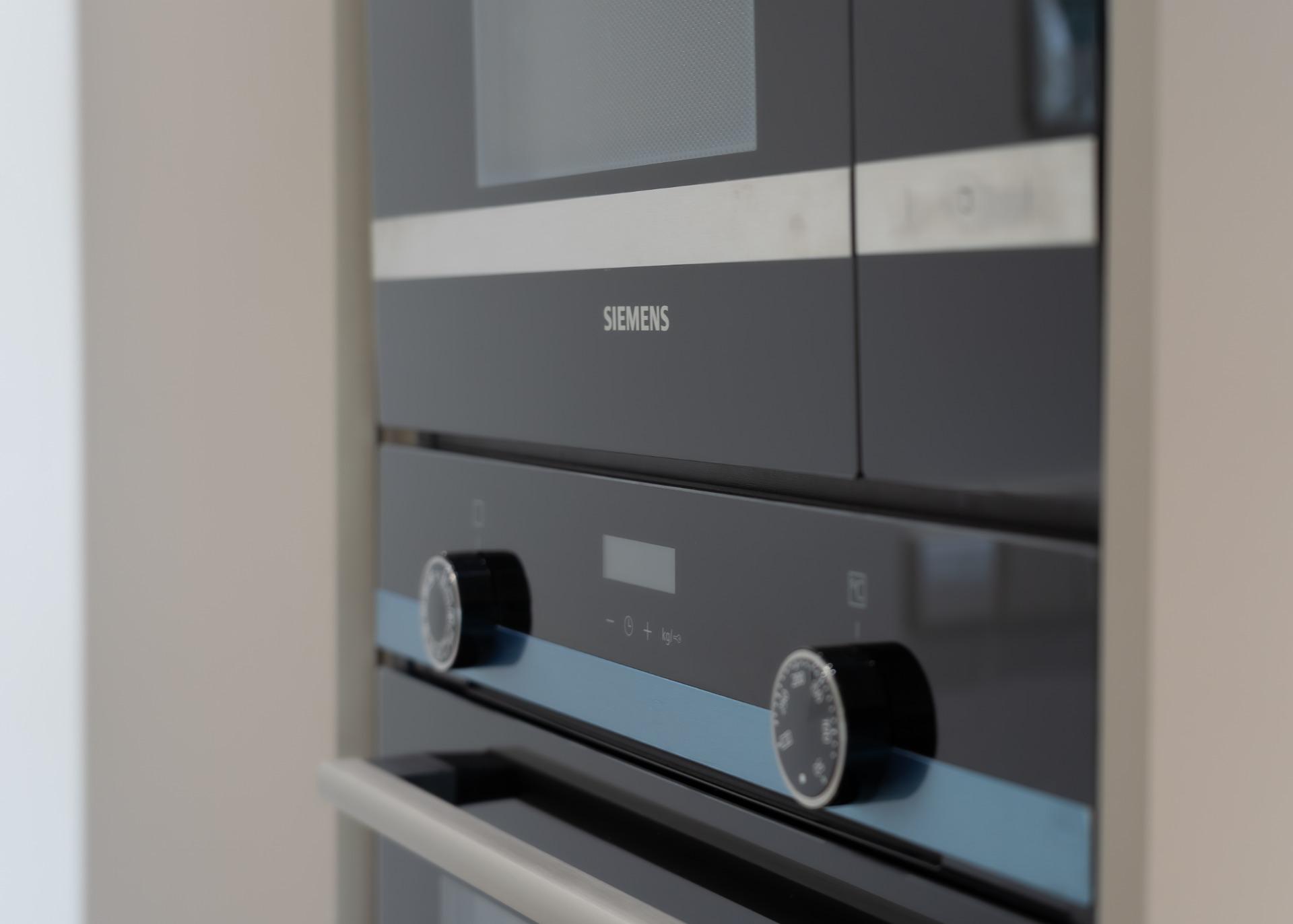 Close-up of a Siemens built-in oven front with control panel and dials visible on a sleek gray surface.