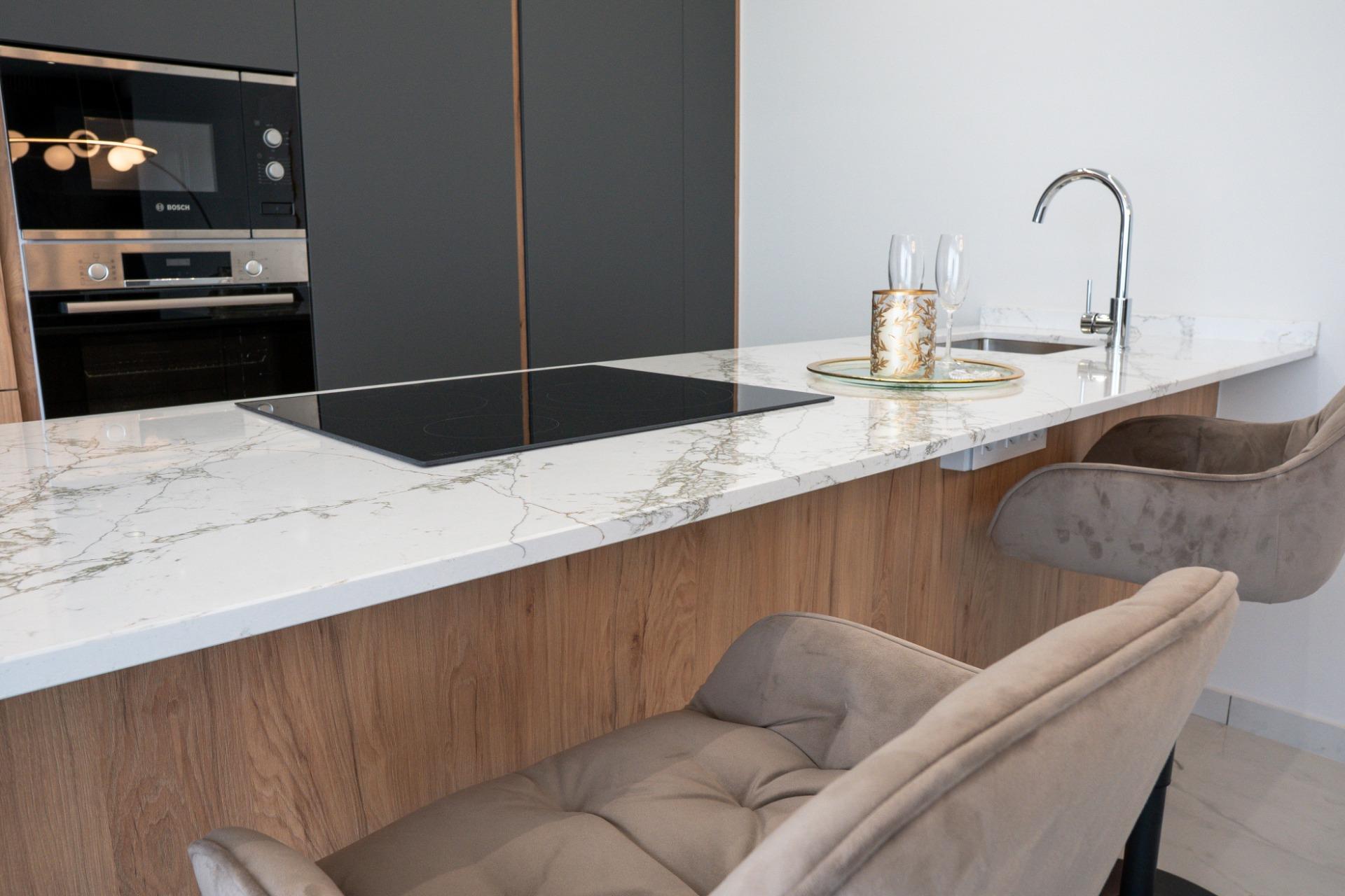 Modern kitchen island with marble countertop, induction cooktop, and built-in stainless steel oven.