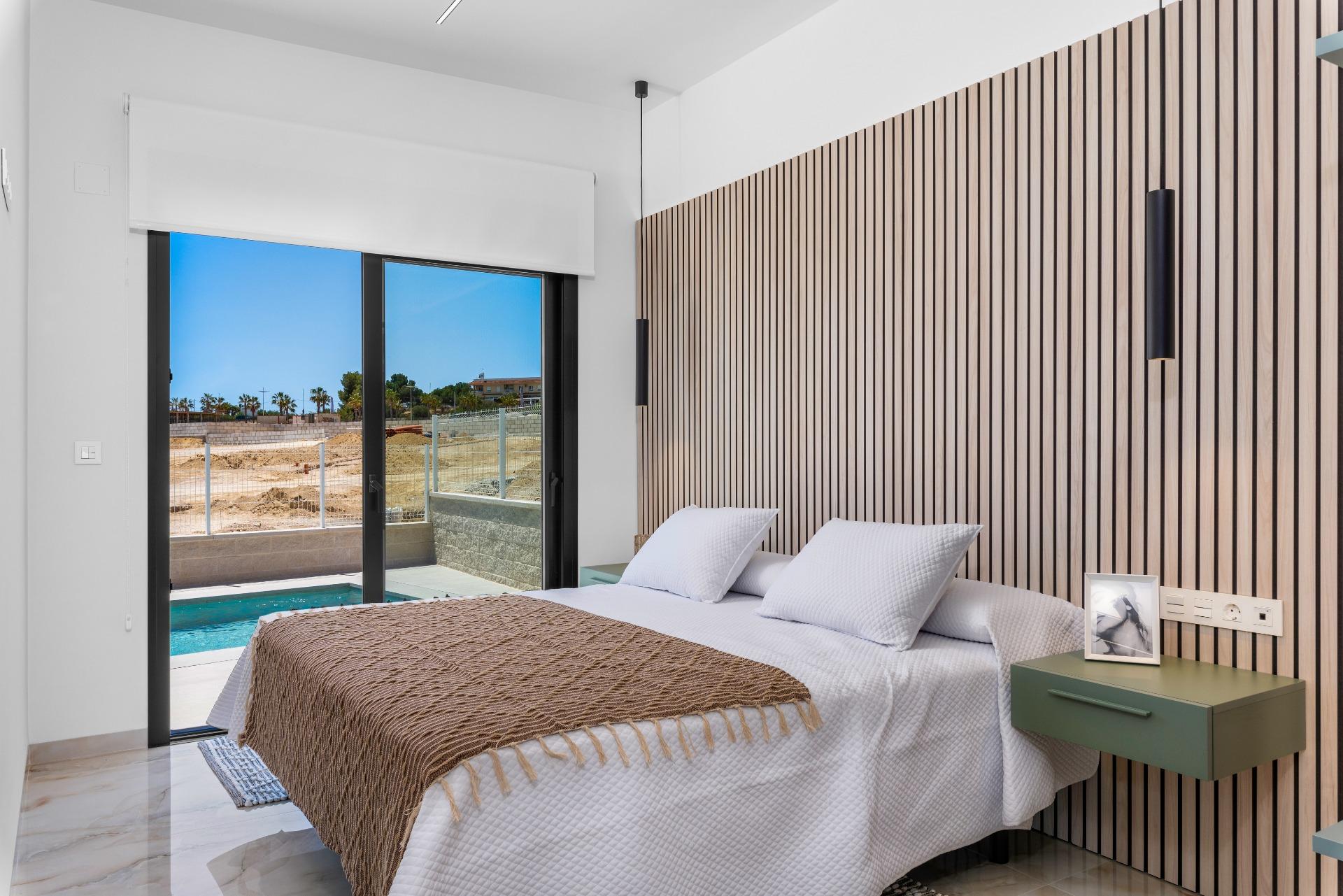 Modern bedroom with a vertical wooden slat wall, white bedding, and sliding glass doors to an outdoor pool area.