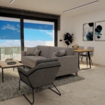 Bright, modern living room with gray sofa and armchair, glass balcony doors, and a dining table visible beyond the seating area.