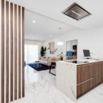 Open-concept living area with a marble floor, wood slat divider on the left, and a marble-and-wood kitchen island in the foreground.
