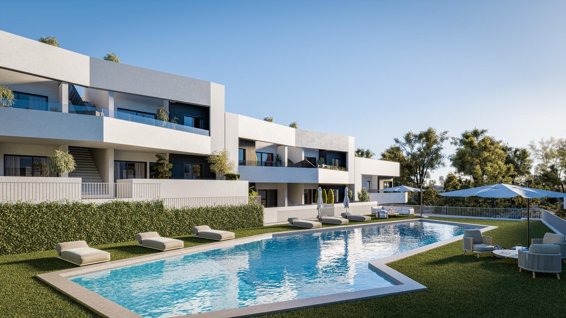 Modern white apartment complex with balconies around a rectangular pool, sun loungers on the lawn, and blue sky above.