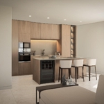 Open-plan kitchen with warm wood cabinetry, an island with bar seating, and built-in oven area under soft ceiling lighting.