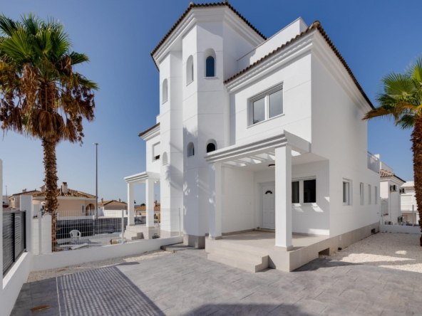 White Mediterranean-style house with arches and palm trees against a clear blue sky, sunny day.