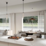 Bright open-plan kitchen and dining area with a marble island, pendant lights, and large windows letting in natural light to a airy space.