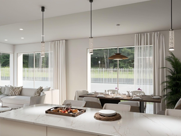 Bright open-plan kitchen and dining area with a marble island, pendant lights, and large windows letting in natural light to a airy space.