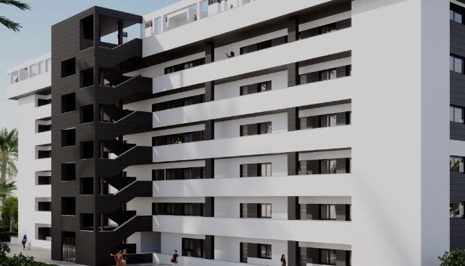 Modern white apartment building with a black external stairwell on the left and multiple balconies.