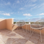 Terrace with peach walls, two woven Acapulco chairs and a small table on tiled floor under a blue sky with clouds.