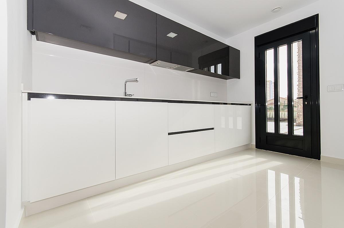 Minimalist kitchen with white lower cabinets, black wall cabinets, and a black-framed glass door by a glossy tiled floor.