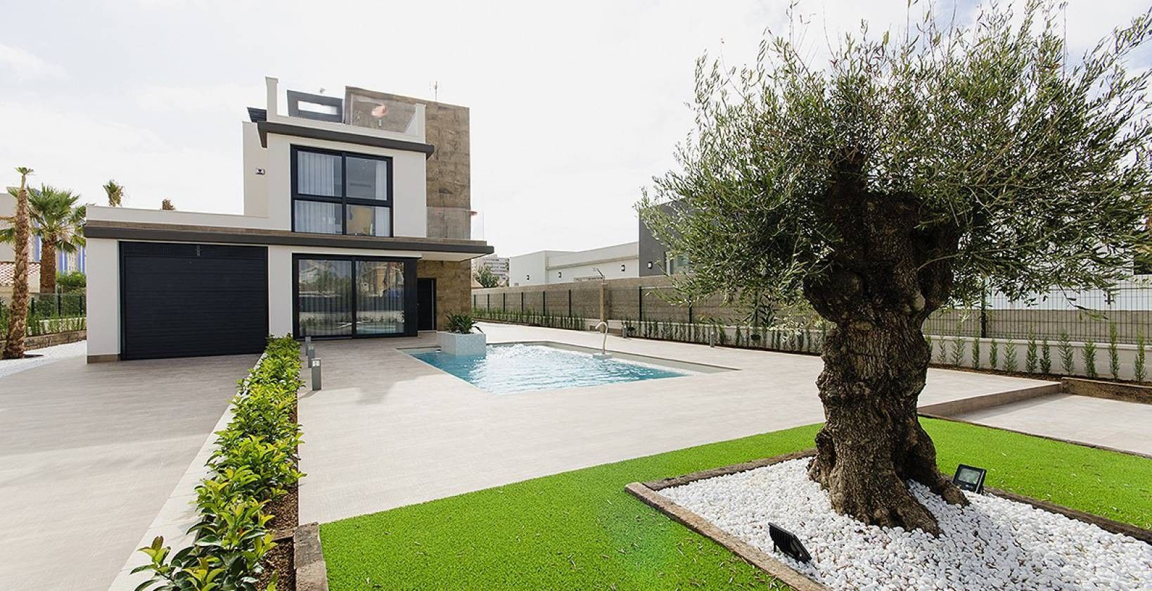 Modern two-story house with large glass windows, a rectangular pool, and a paved yard.