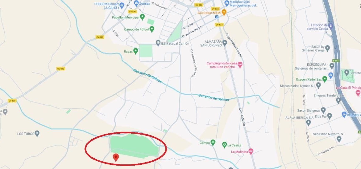 Map highlighting a green rectangular park along a curved blue river, circled in red with a nearby pin